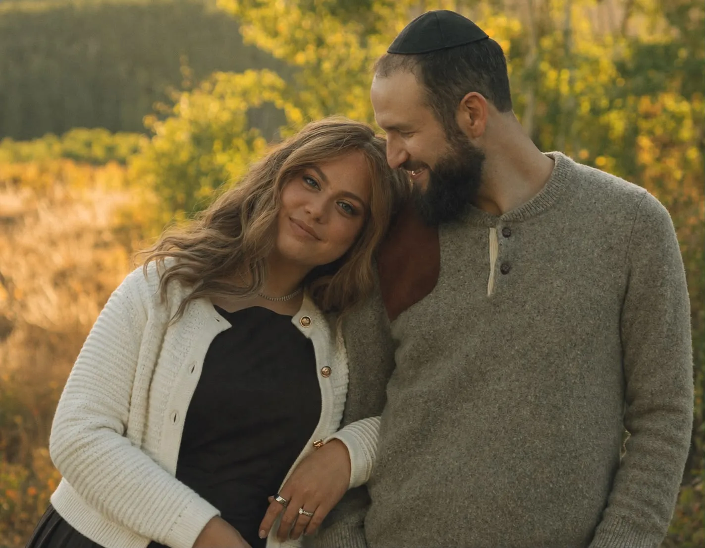 Aliza and Rabbi Meir Jacobs standing close together in a golden autumn field, her head resting toward him as he smiles.